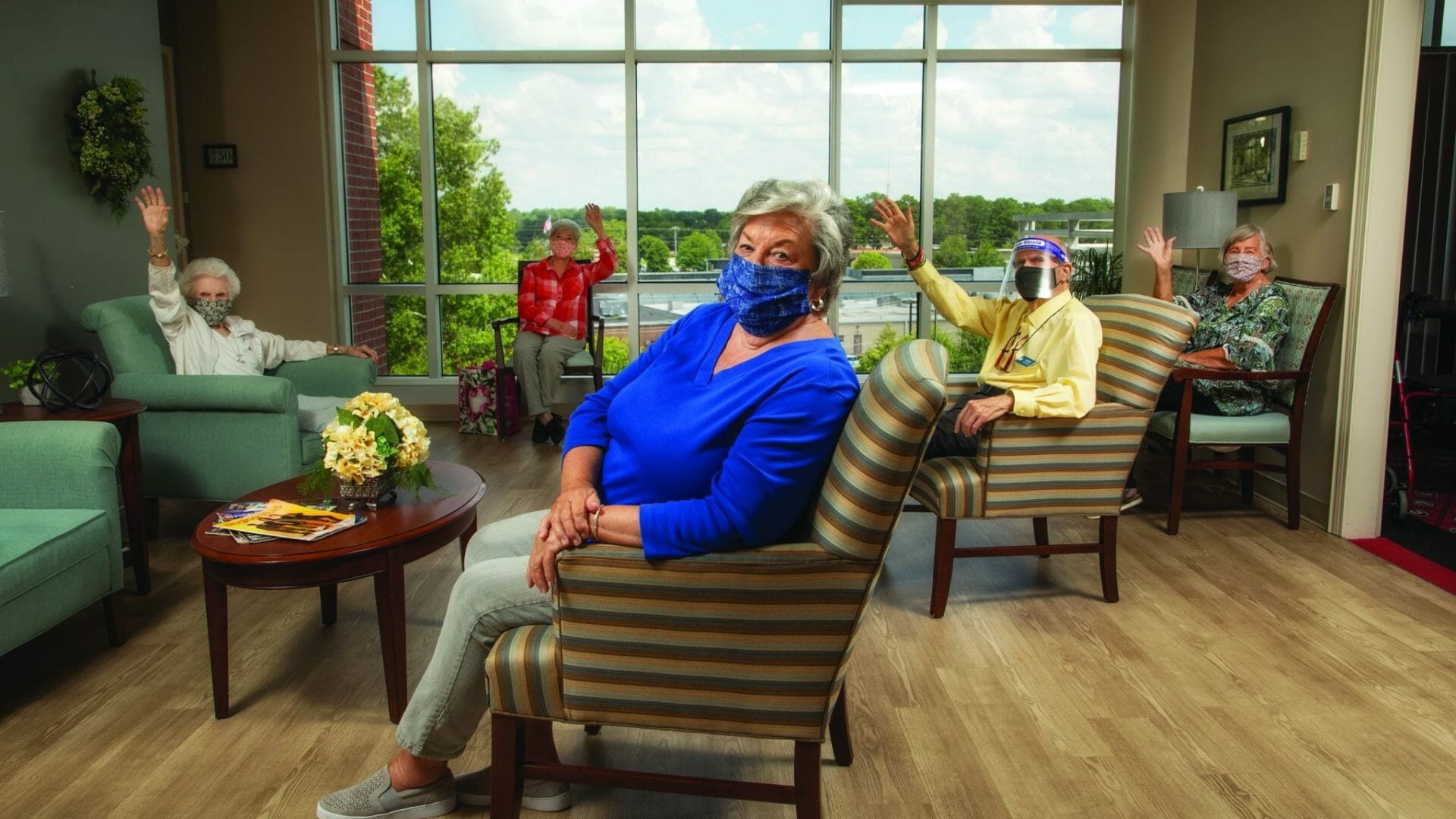 Weslet Woods Athens - Seniors in the living area waving at the camera wearing masks